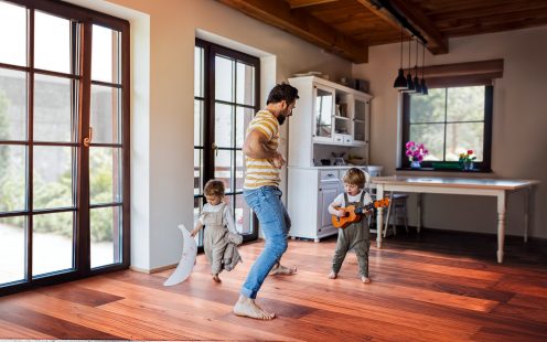 A father and toddler children playing indoors at home.