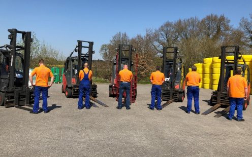 A picture containing workers on production site wearing T-Shirts with safety rules written on the backs.