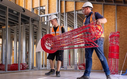 Two installers carrying a rolled prefabricated underfloor heating mat to the installation site | Pipelife